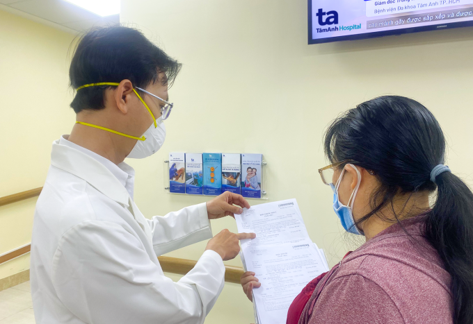 Bác sĩ Phan Tuấn Trọng hướng dẫn người nhà chăm sóc cho chị Mỹ trước khi xuất viện. Ảnh: Nguyễn Trăm