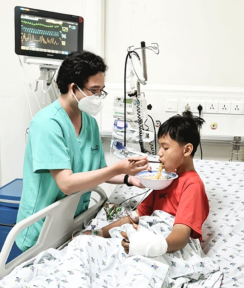 Bé trai hồi phục sau ba ngày điều trị tích cực, được bác sĩ Nguyễn Đạt Thịnh, Khoa Hồi sức Tích cực Chống độc, nấu mì gói cho ăn. Ảnh: Bệnh viện Nhi đồng Thành phố