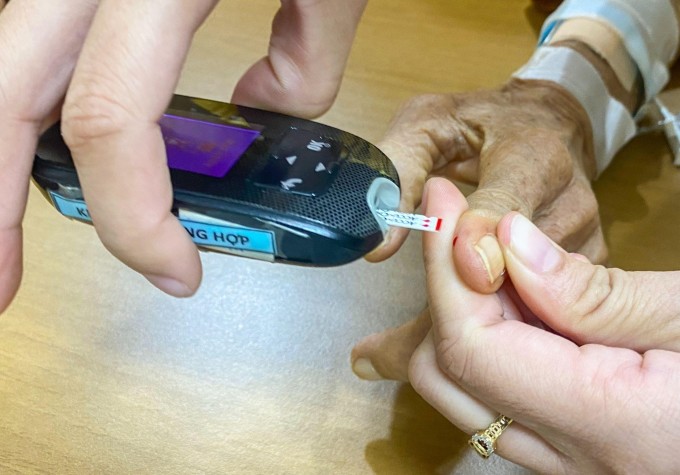 Nhân viên y tế Bệnh viện Đa khoa Tâm Anh TP HCM lấy máu ngón tay để đo đường huyết cho ông Hồng vào đầu tháng 5. Ảnh: Nguyễn Trăm