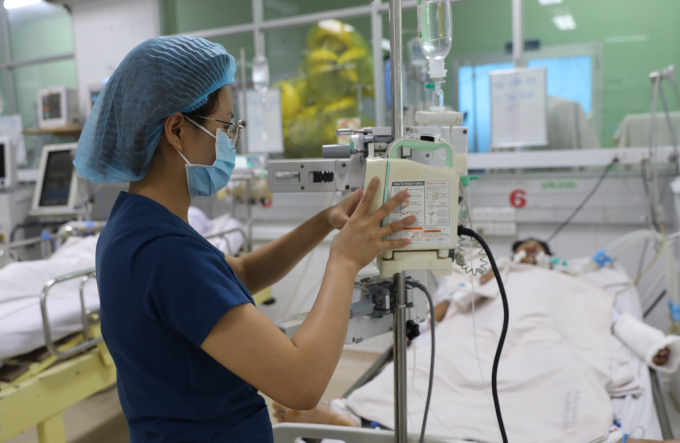 Nhân viên y tế điều chỉnh dịch truyền cho một bệnh nhân sốt xuất huyết nặng tại Bệnh viện Bệnh Nhiệt đới TP HCM, ngày 28/6. Ảnh: Quỳnh Trần