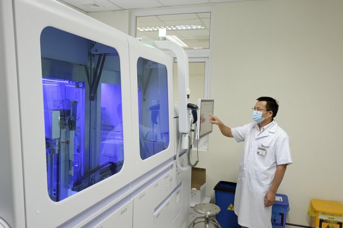 Chuyên gia vận hành máy phân tích sinh học phân tử, tại Bệnh viện Bệnh nhiệt đới Trung ương, ngày 26/7. Ảnh: Văn Phong