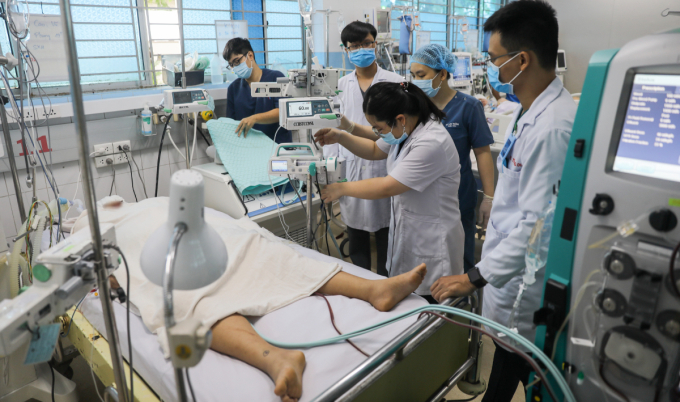 Y bác sĩ khoa ICU, Bệnh viện Bệnh Nhiệt đới tập trung lắp máy móc điều trị cho một bệnh nhân nữ dư cân, tái sốc sốt xuất huyết nguy kịch, hồi cuối tháng 6. Ảnh: Quỳnh Trần